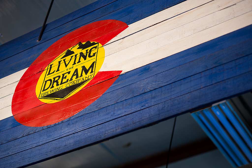 Colorado state flag with Living The Dream Brewing logo